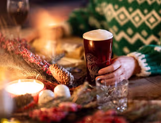 person holding a pint of Young's beer at a festive table
