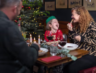 family laughing and eating Christmas dinner at a Young's pub