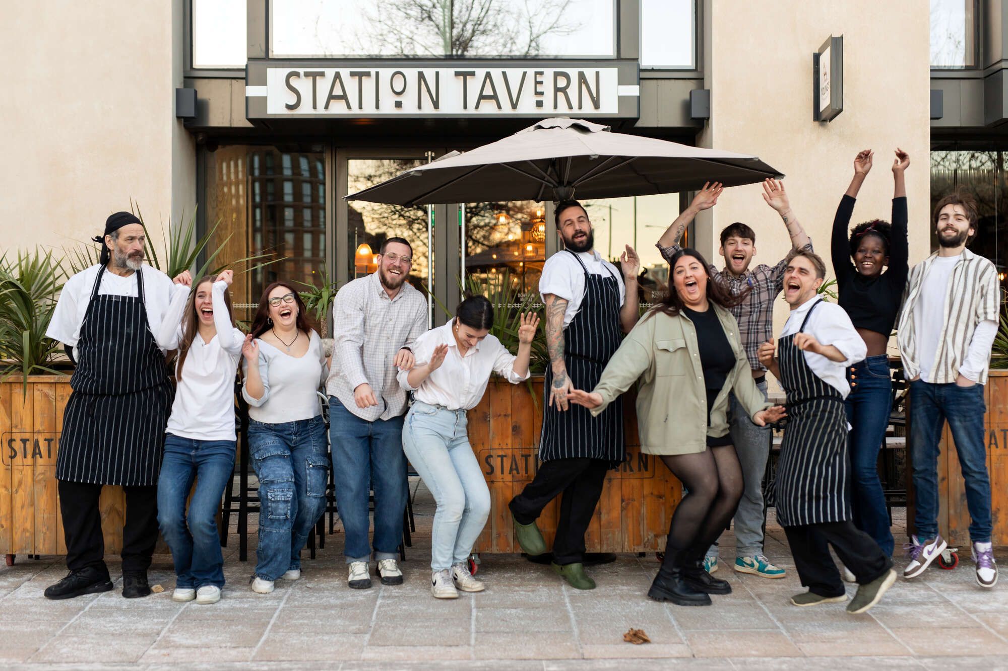 group of Young's staff dancing and jumping in front of Station Tavern, a Young's pub