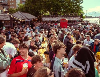 People enjoy an outdoor space on the Thames at a pub