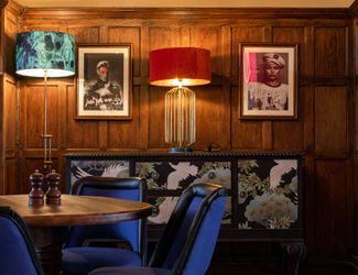 Paintings and wall fixtures on wall next to tables at Cock tavern