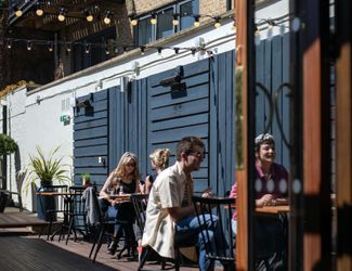 Outside seating area of Cock Tavern with people sat at tables.