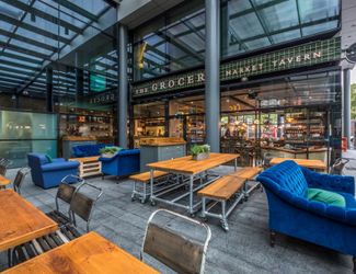 outdoor covered pub seating area with picnic tables and comfy blue chairs