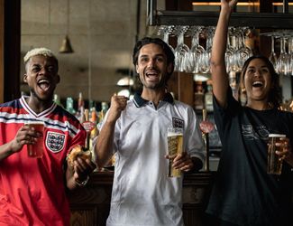 friends in a Young's pub drinking pints and cheering
