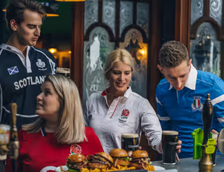 group of friends sharing pints of Guinness, burgers, and fries