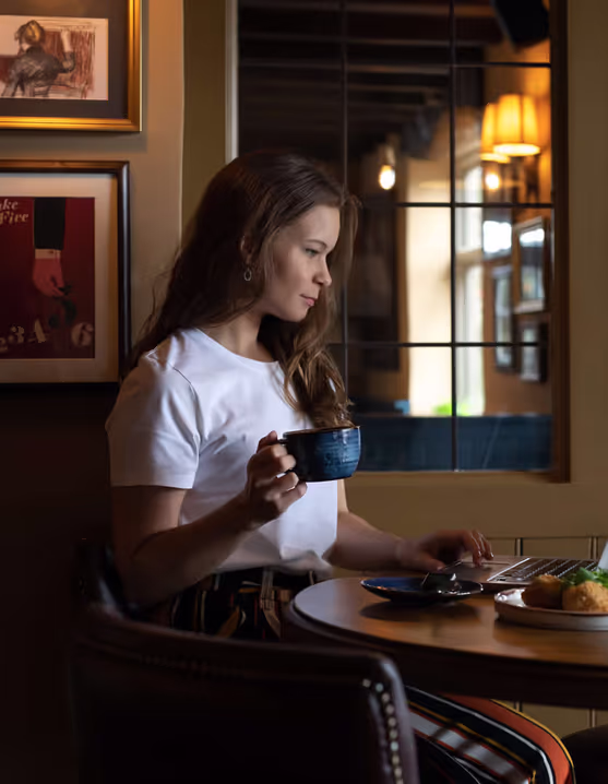woman working from a Young's pub with a cup of tea and plate of food