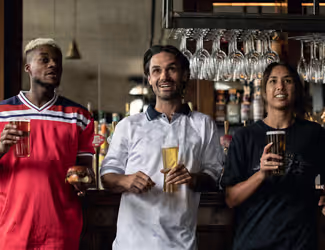 three friends watching the game with beers at a Young's pub