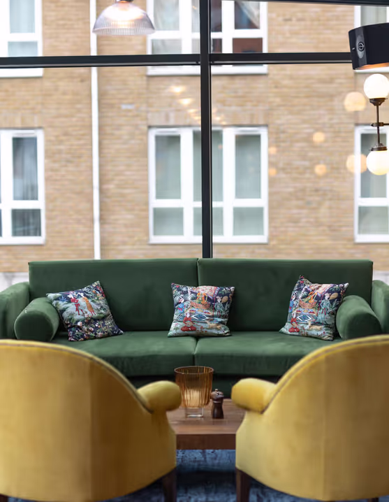 living room with two yellow chairs, a green couch, and a TV