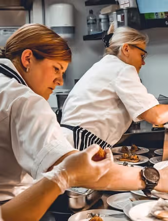 Natalie Coleman plating meals alongside other chefs in the kitchen