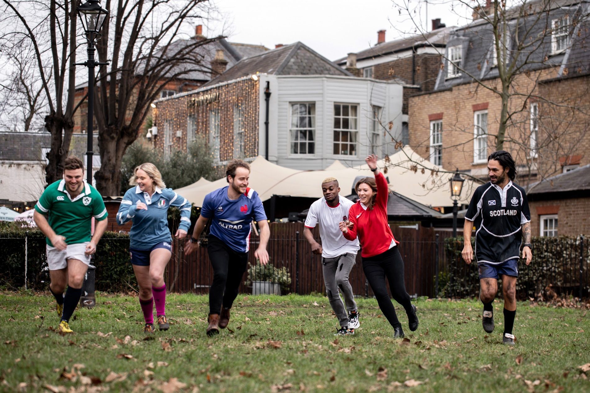 group of people wearing rugby jerseys and running in a yard